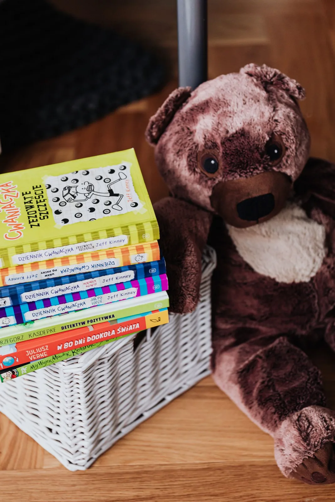 Teddy bear alongside colorful children's books in a decorative basket.