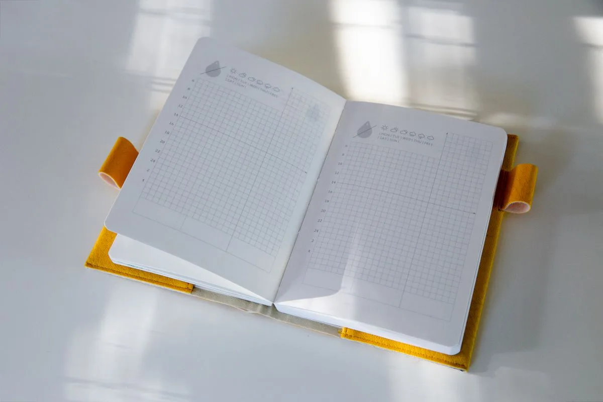 Open grid-pattern notebook on a white surface with natural lighting, ideal for planners.