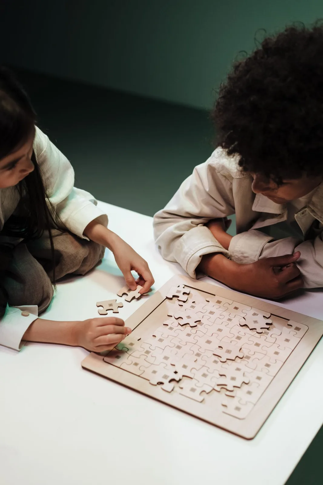 Two children solving a jigsaw puzzle together, focused on teamwork and intellectual development.