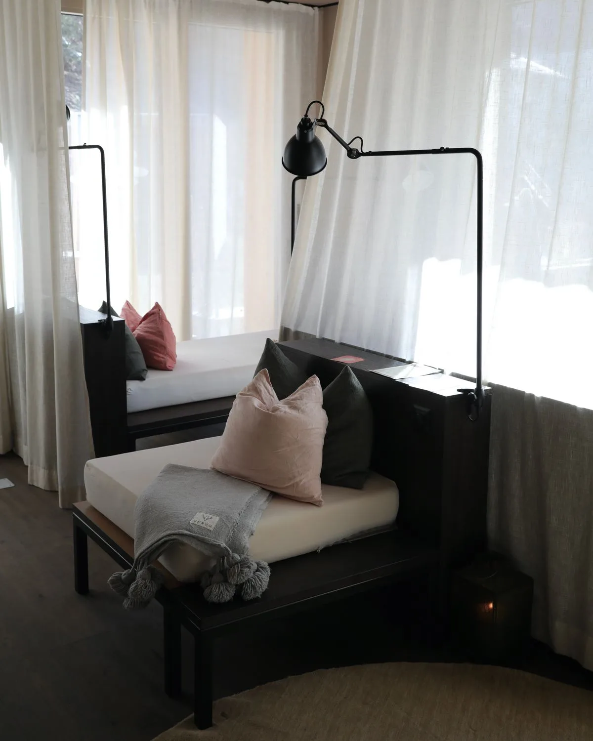 Inviting reading nook with soft cushions, modern lighting, and sheer curtains, perfect for relaxation.