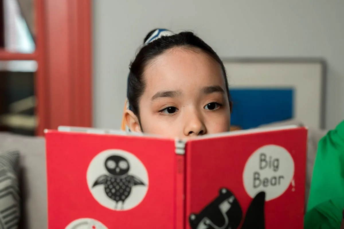 A child attentively reading a book in a cozy indoor setting.