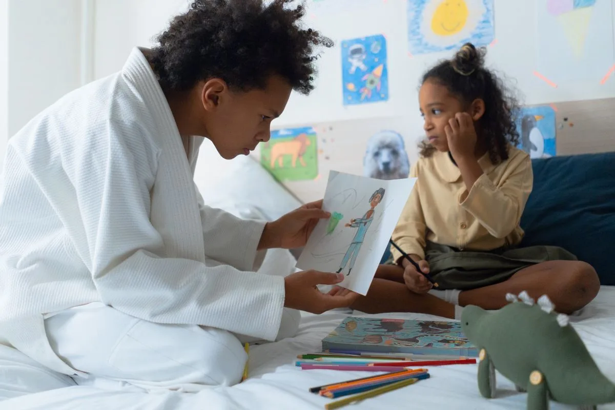 Siblings enjoy artistic drawing time in a cozy bedroom setting.