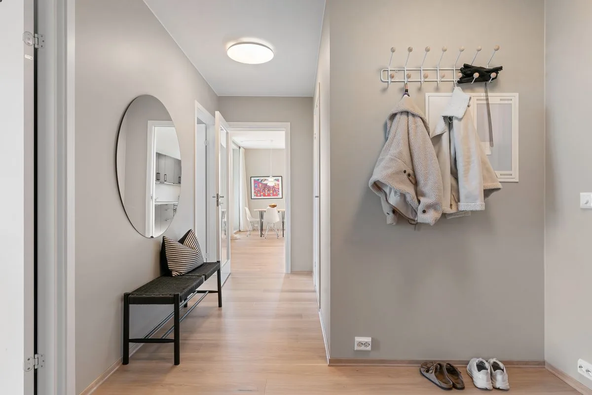 A contemporary hallway with minimalist decor featuring coats, shoes, and a stylish mirror.