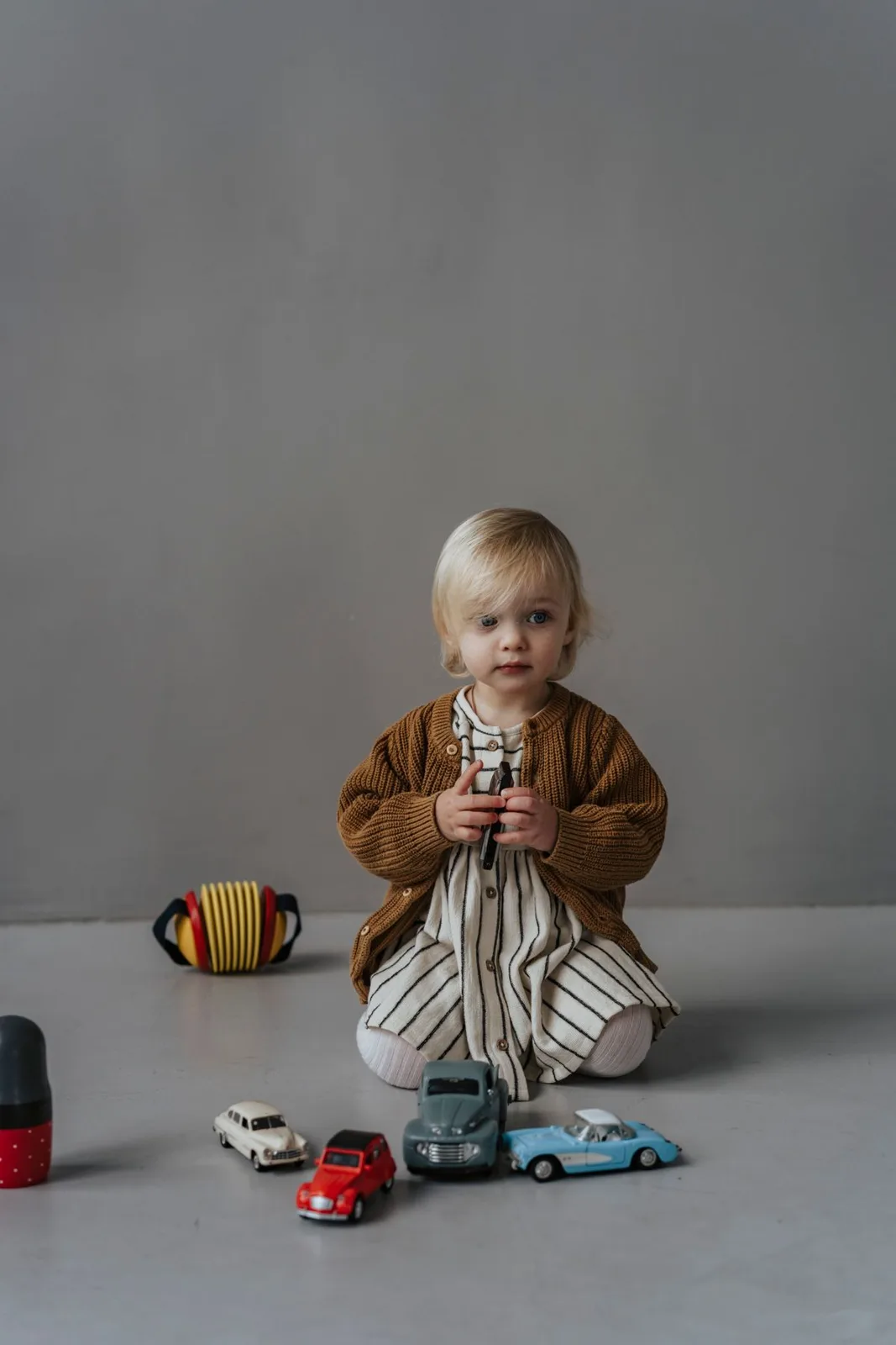 A young child holding toy cars indoors.