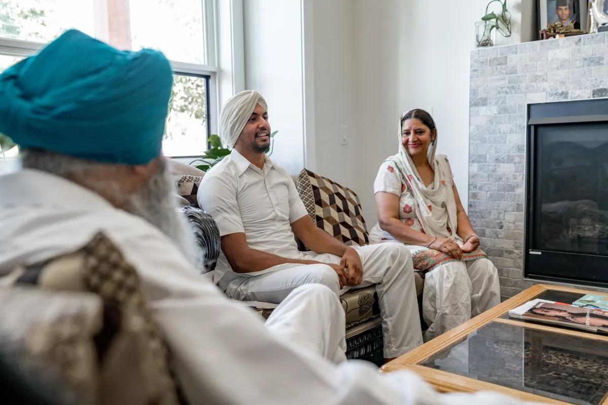 Family members in traditional attire having a conversation on the sofa in a bright living room.