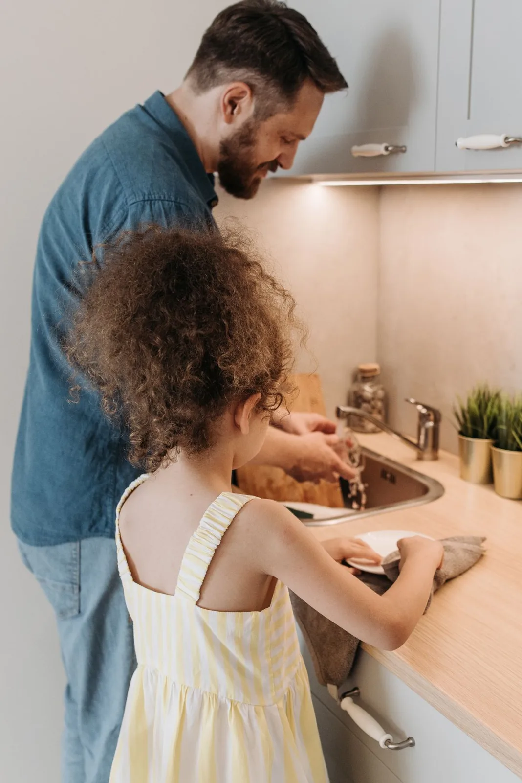A dad and his daughter enjoy a moment together doing kitchen chores.
