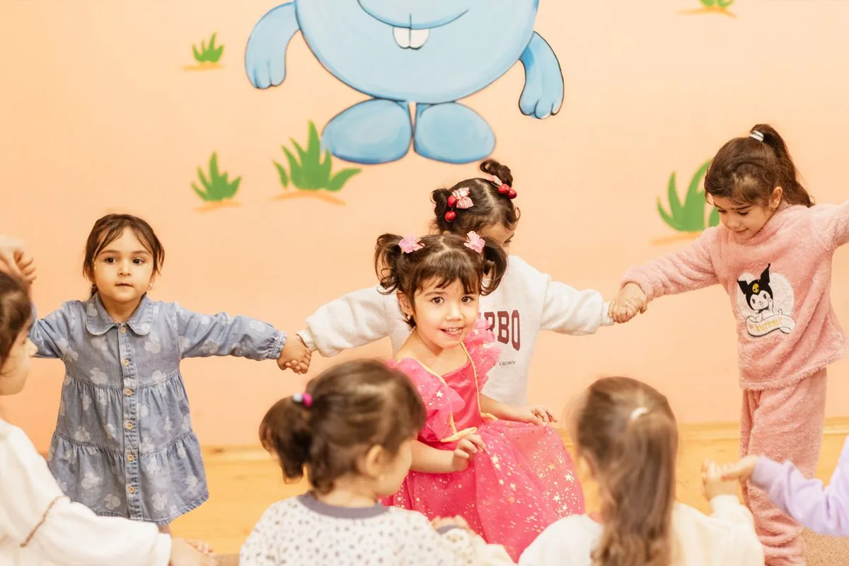 Children holding hands in an indoor circle game.