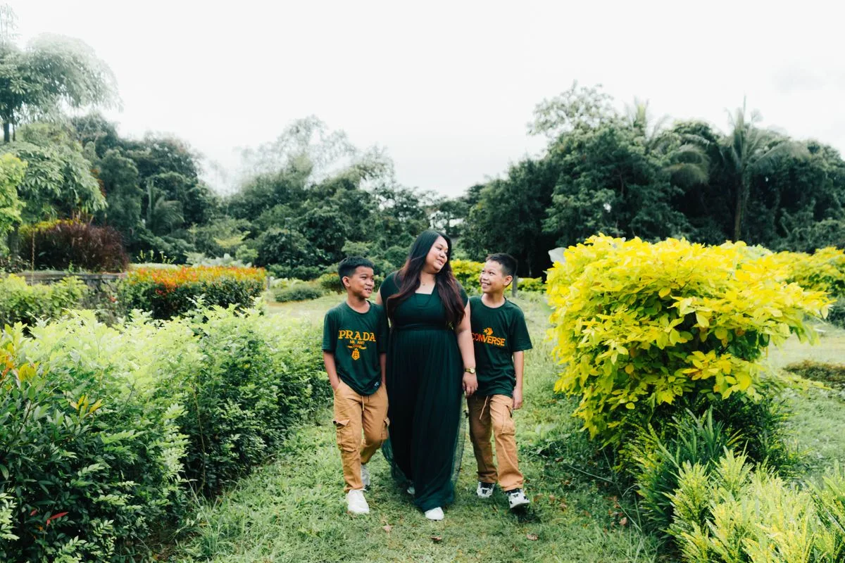 Mother and sons enjoy a walk through a lush green garden.