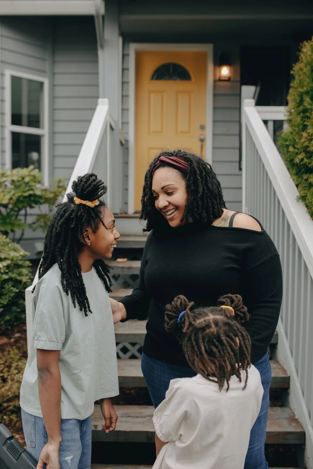 A mother and her daughters enjoying a cheerful moment together outdoors.