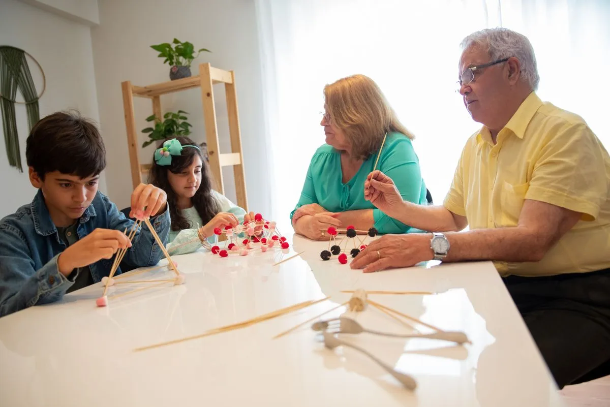Grandparents and grandchildren engage in a creative building activity indoors.